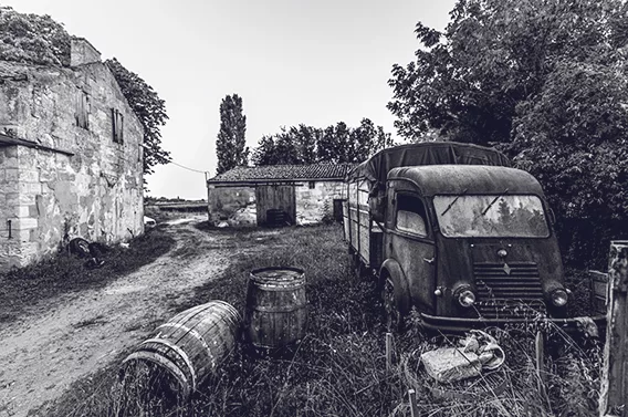 Old truck and barrels in front of rural buildings